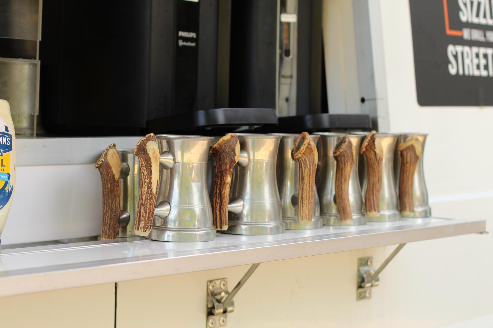 A line of metal tankards ready at the Fromage Fiesta service hatch.