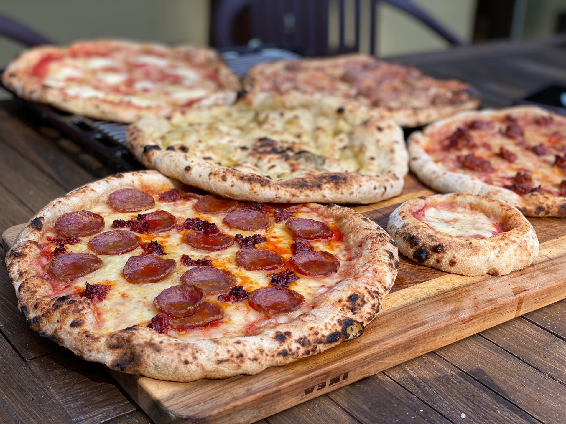 A board and grill loaded with freshly baked pizzas.