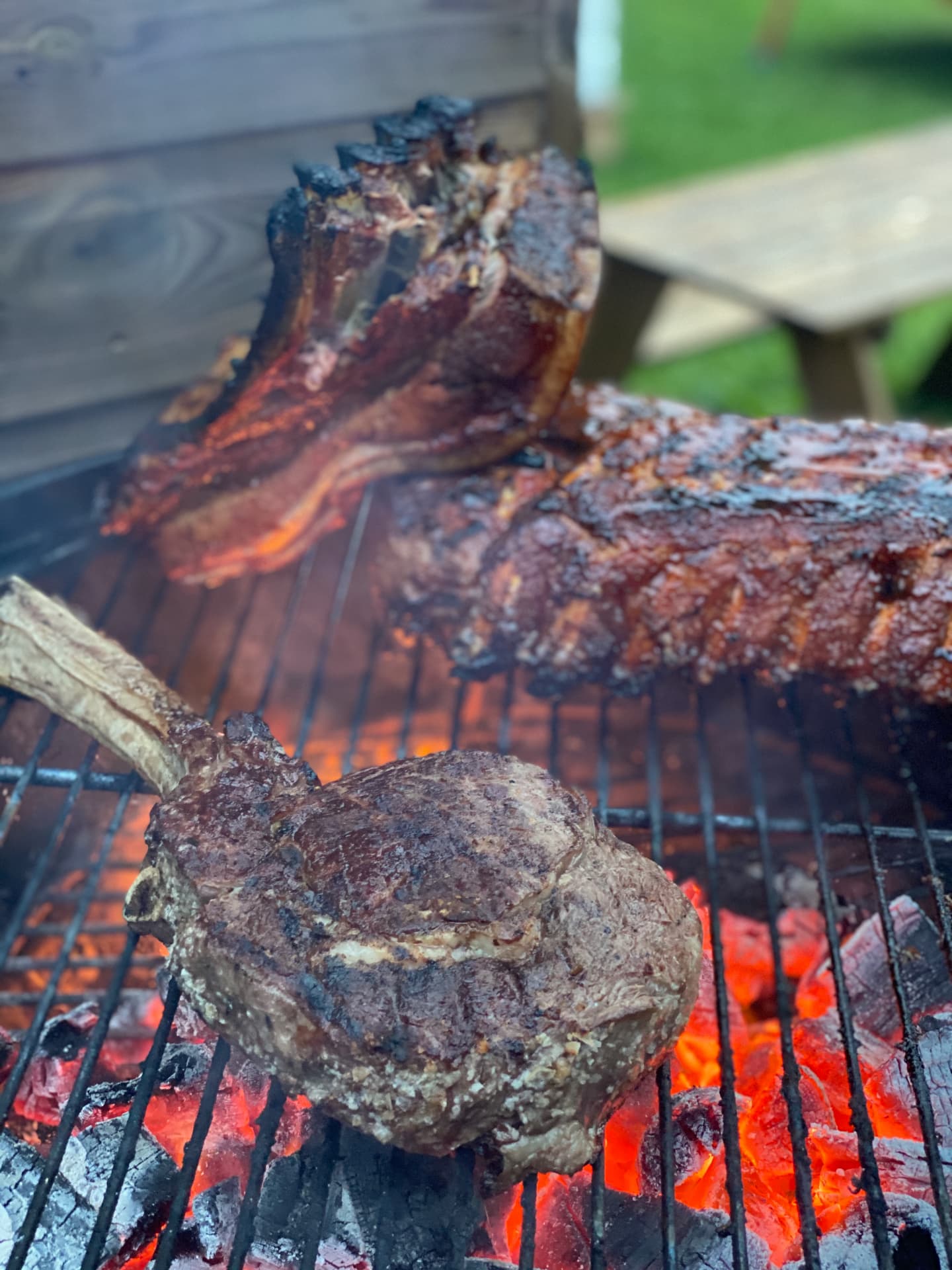 Steaks and ribs grilling over glowing coals.
