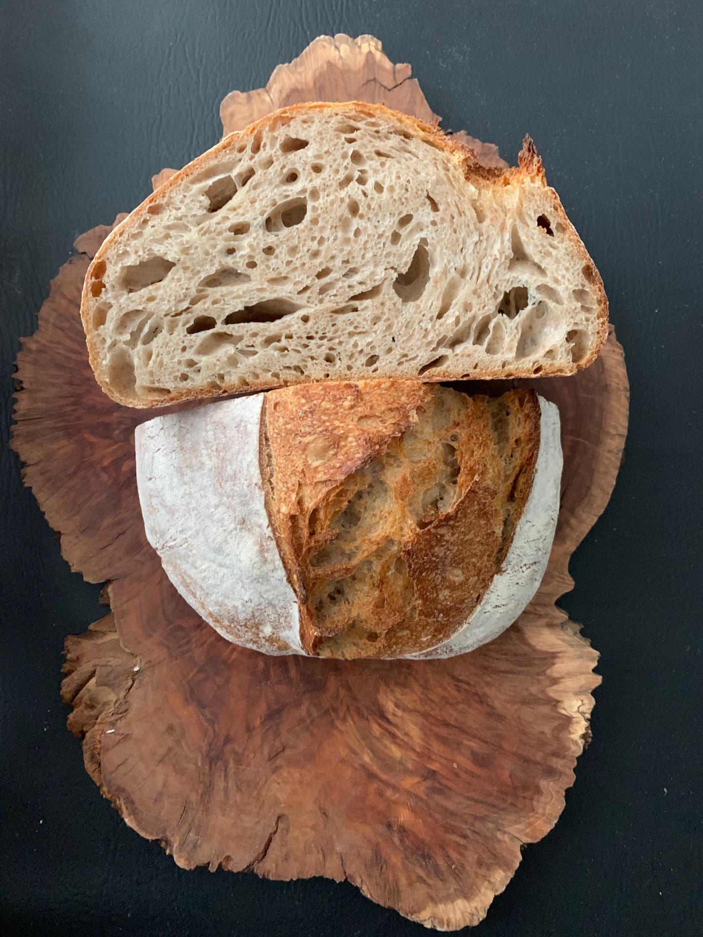 Slices of dark, open-crumbed sourdough on a wooden board.