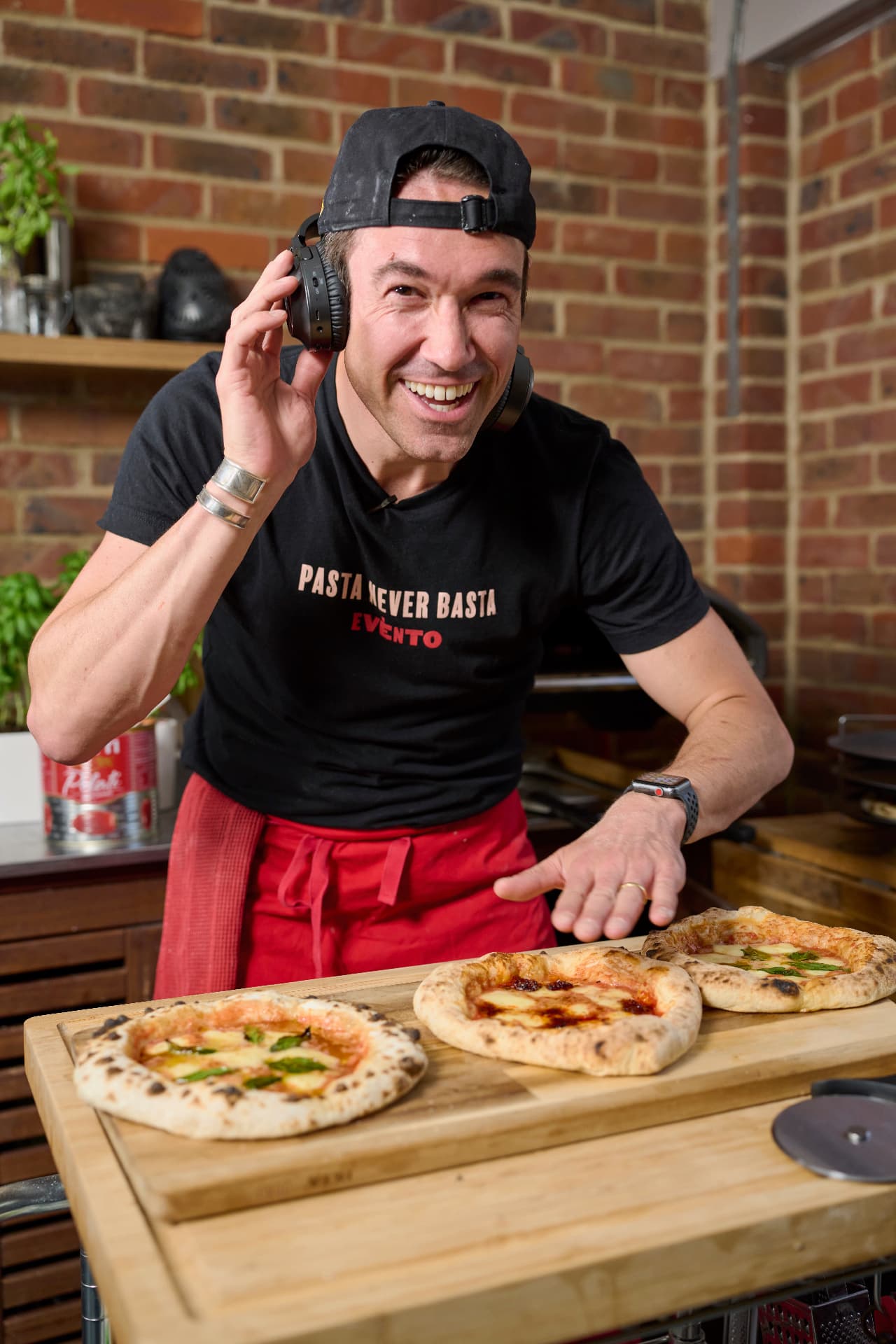 Gregory in a headset presenting freshly made pizzas.