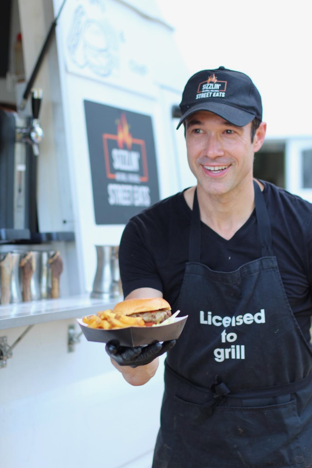 Gregory serving a burger and fries from the Sizzlin' Street Eats truck.