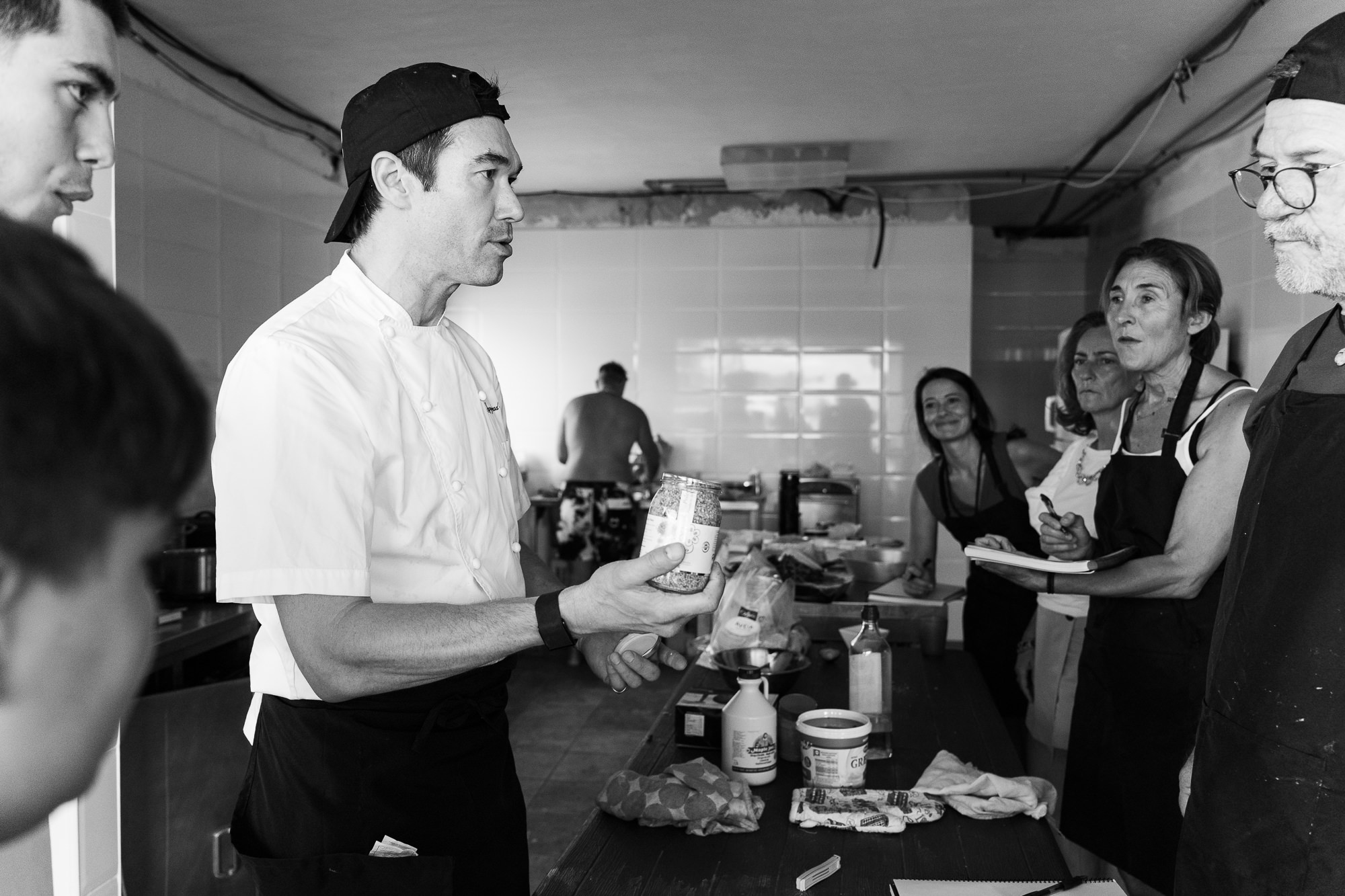 Gregory leading a group of cooks through an idea around a busy prep table.