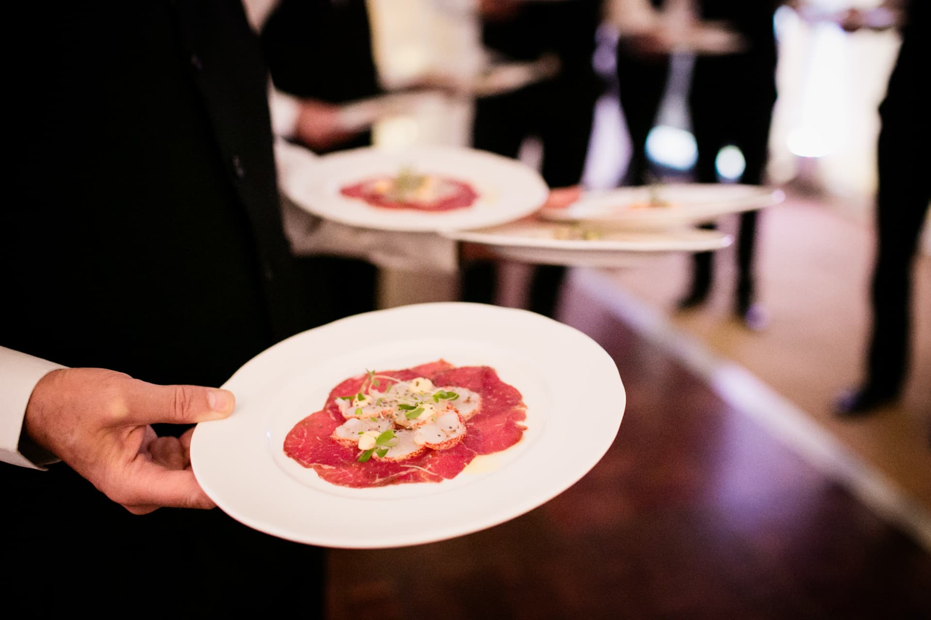 A plated carpaccio being served at a celebration.
