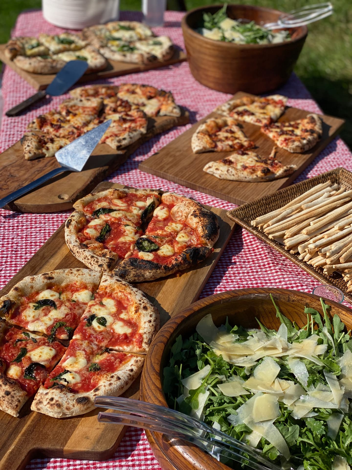 Pizzas and salads spread across a long checked table in the garden.