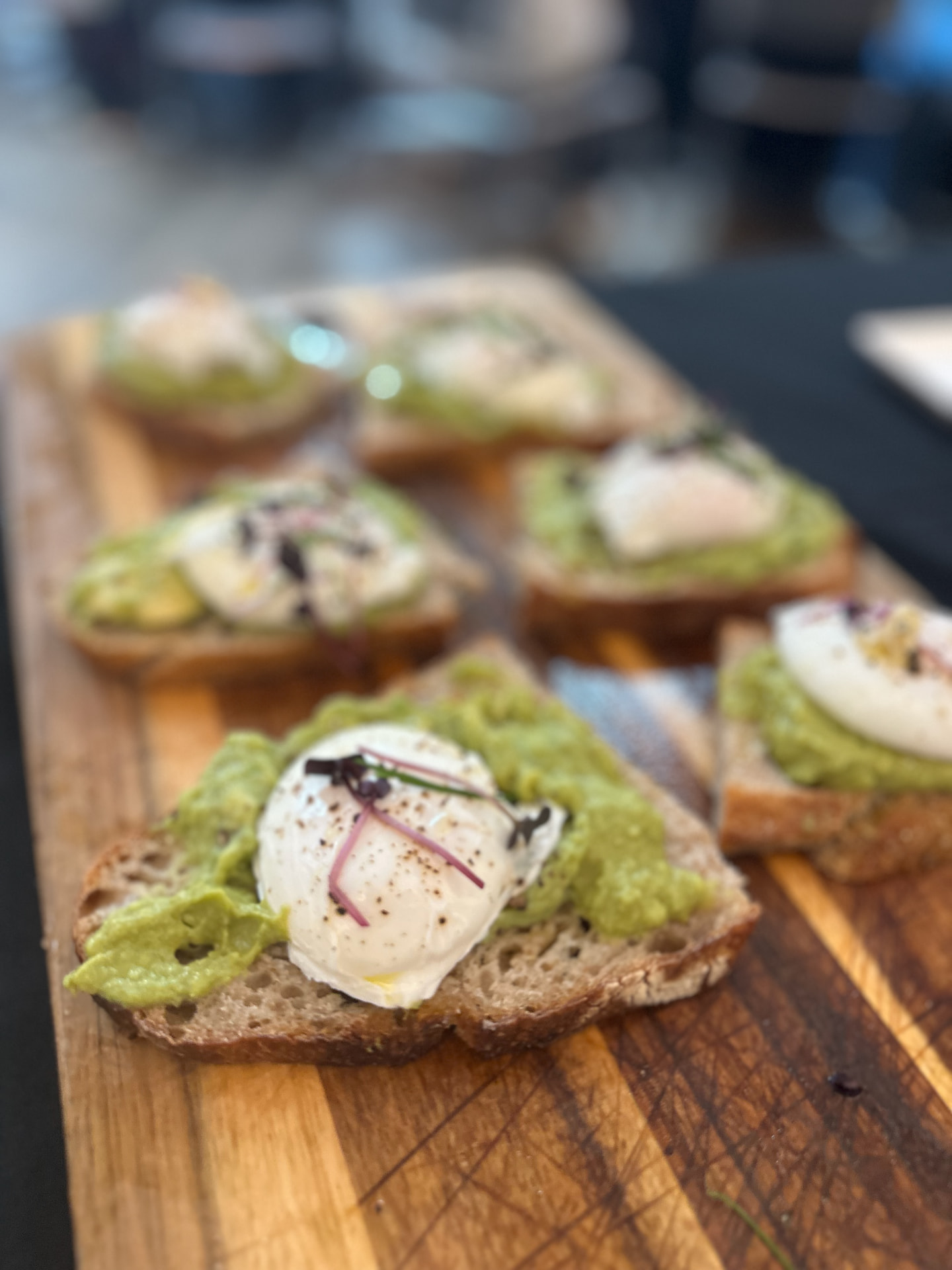 Poached eggs on smashed avocado and sourdough, served on a wooden board.