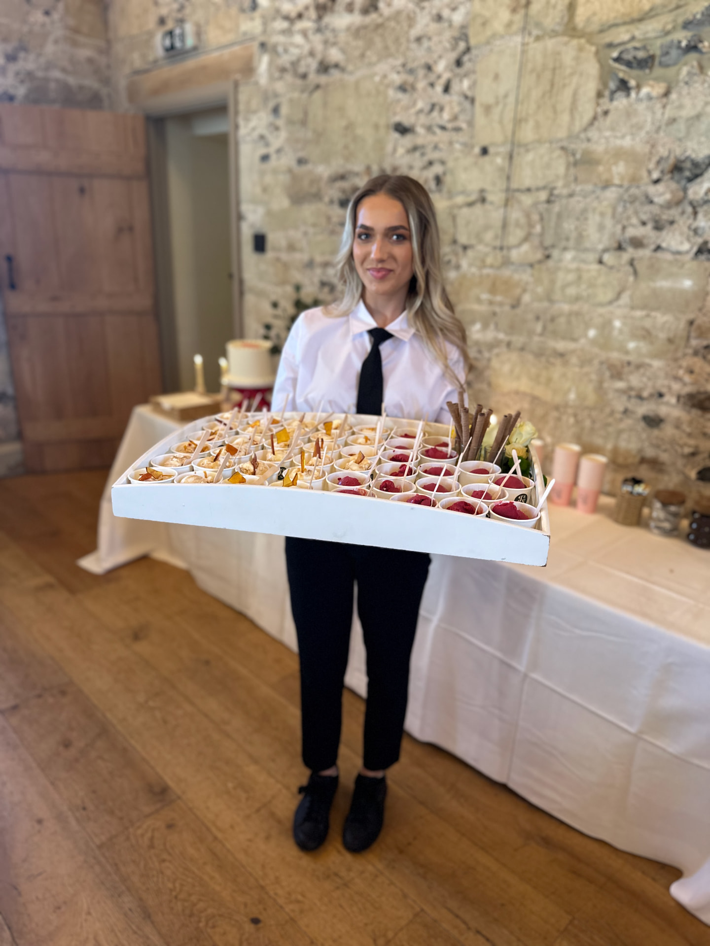 A member of the service team carrying a generous tray of desserts.