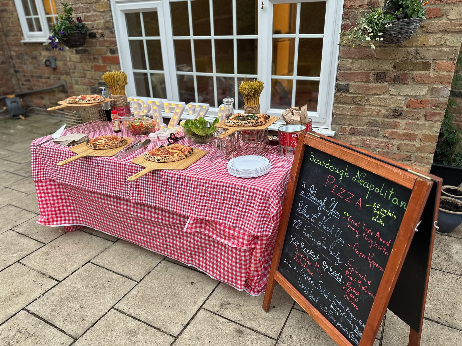 Fresh pizzas spread across a red checked table for a crowd.