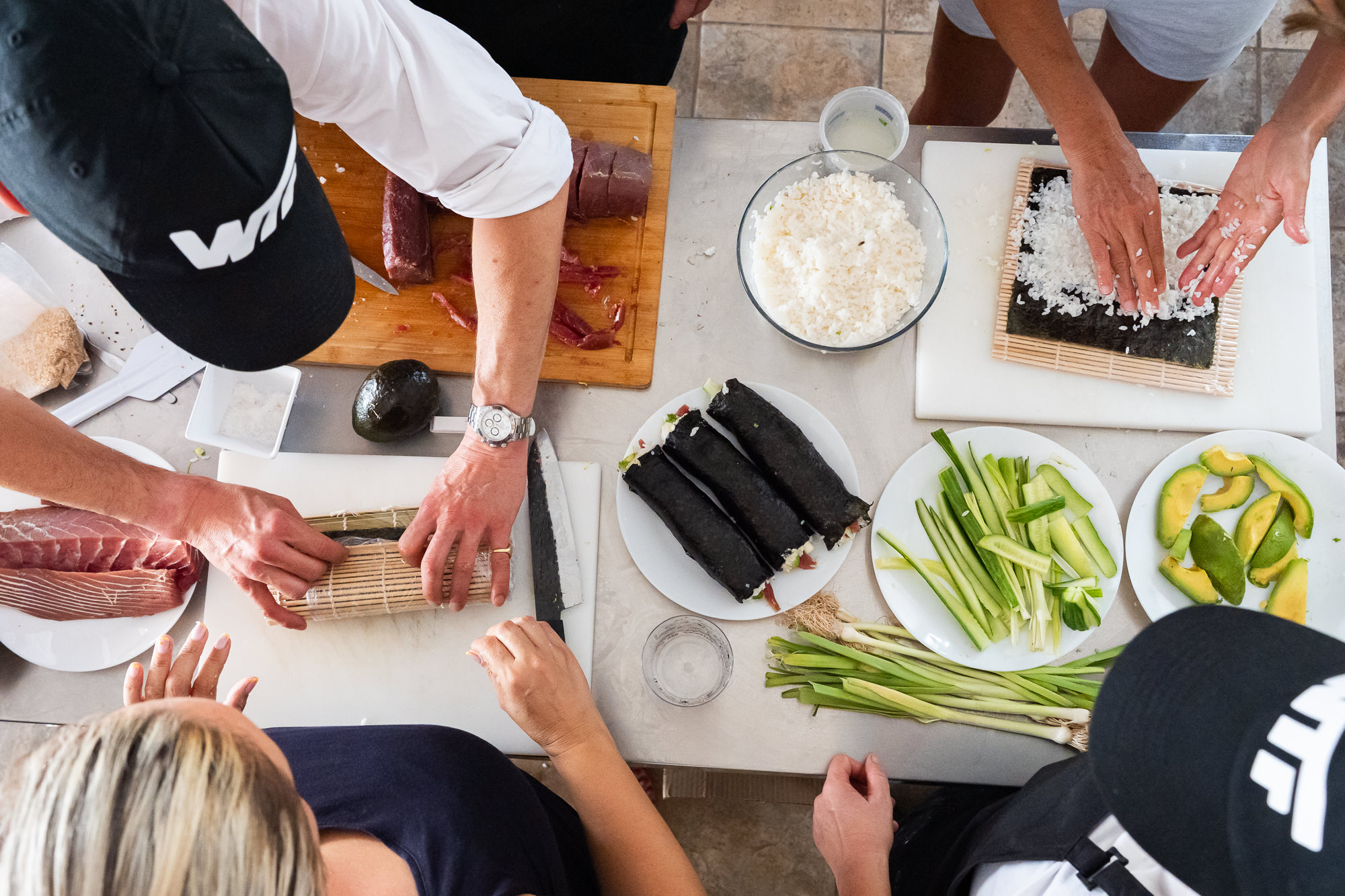 Overhead view of hands rolling sushi around a shared table with Gregory.