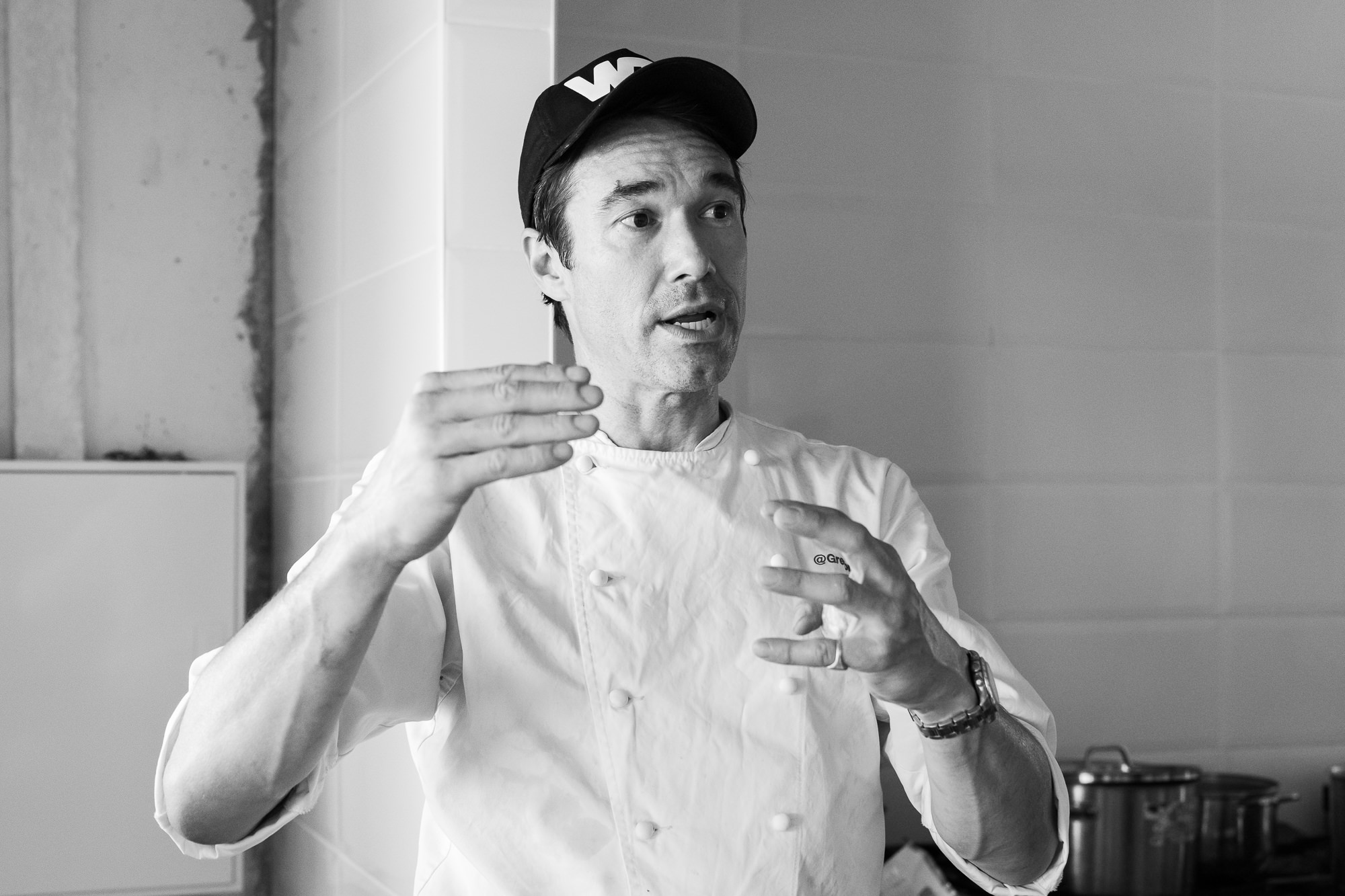 Black-and-white portrait of Gregory mid-sentence in his chef whites.