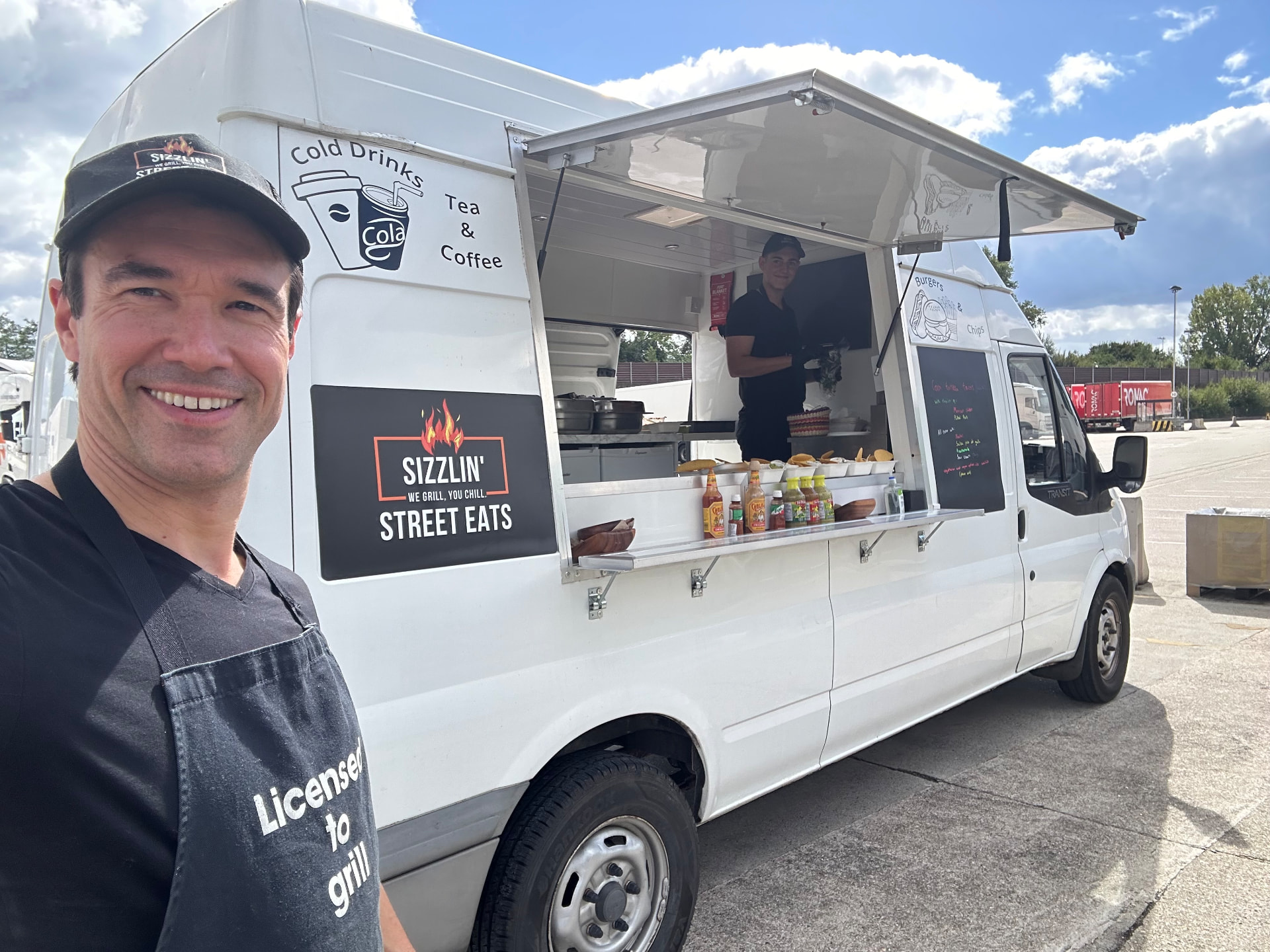Gregory in a Licensed to Grill apron beside the Sizzlin' Street Eats food truck.