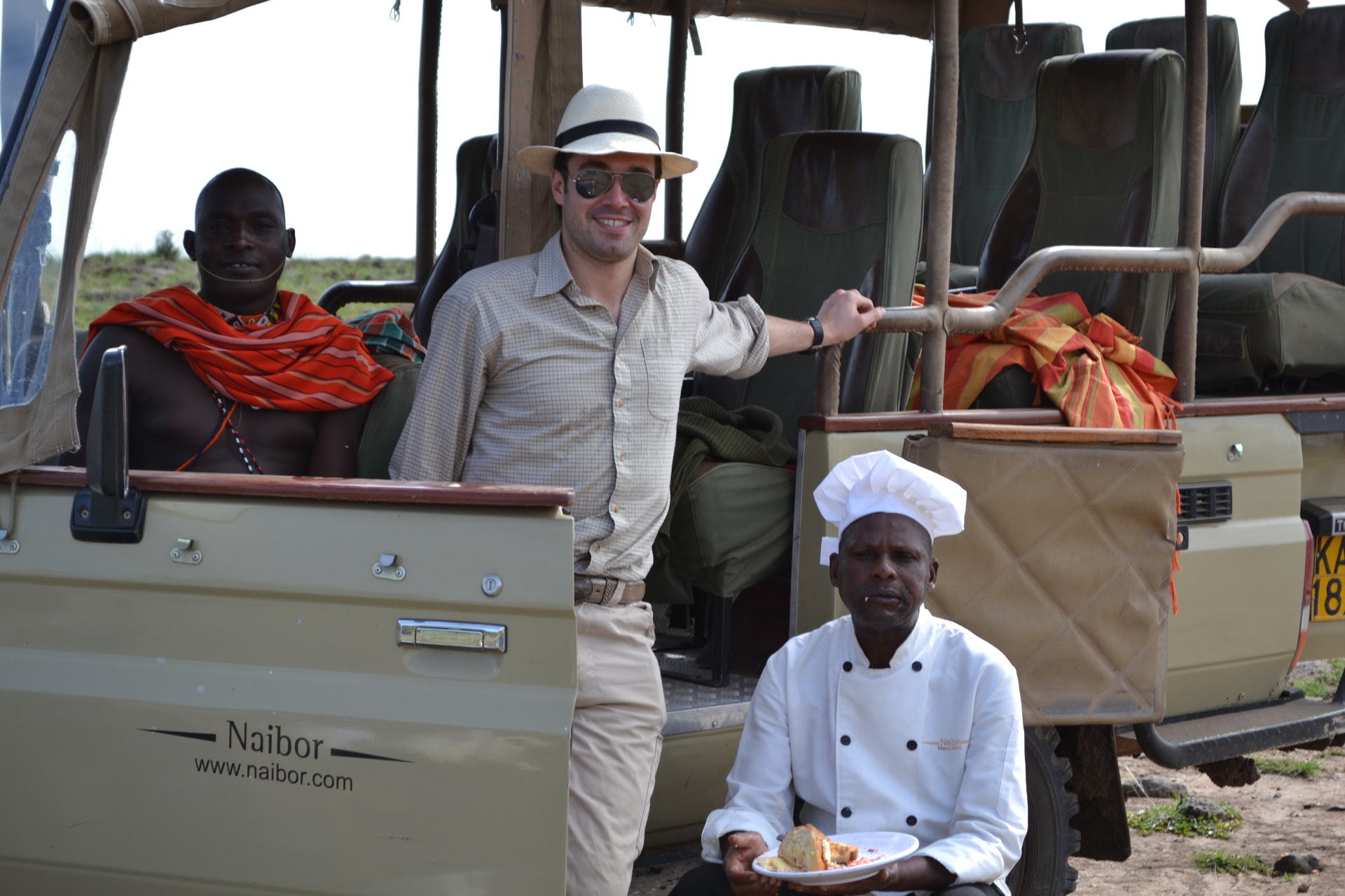 Gregory with a guide and chef beside a safari vehicle.