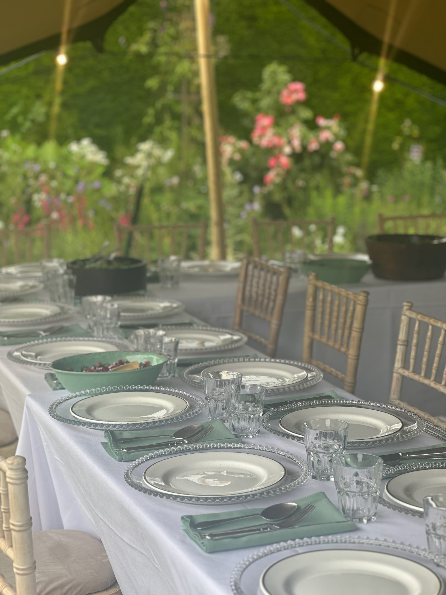 A long garden table laid beneath a canvas canopy.