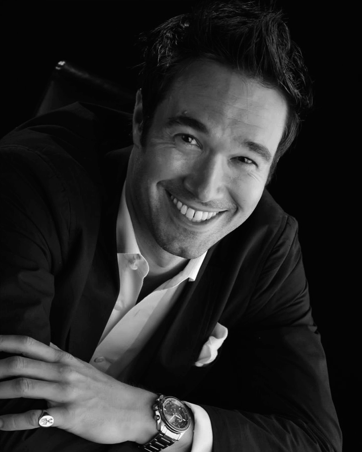 A black-and-white portrait of Gregory in black tie.