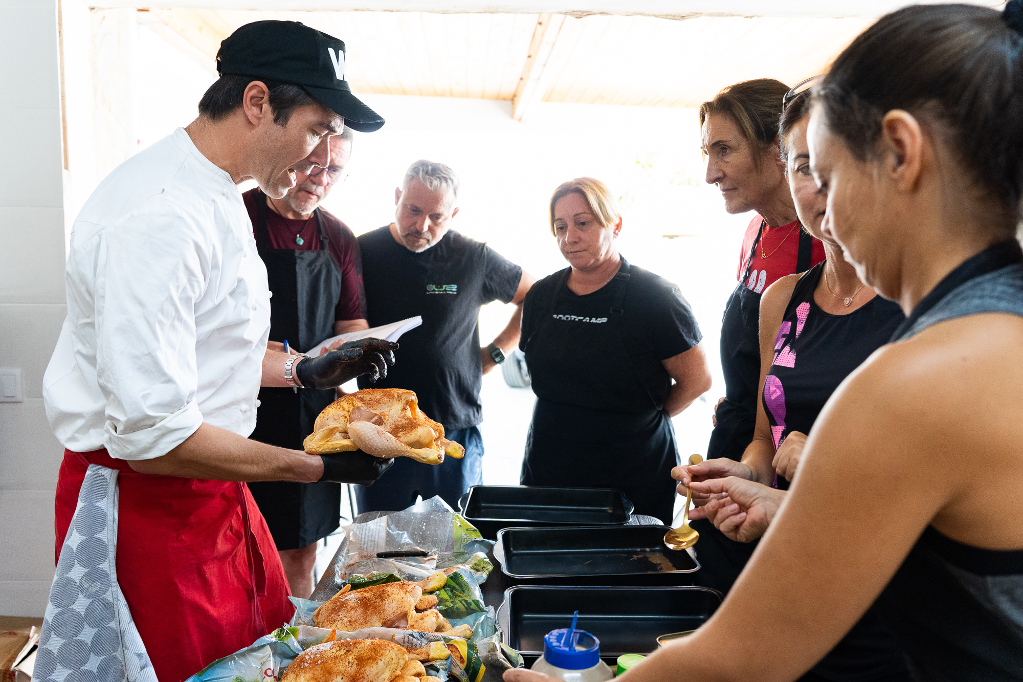 Gregory demonstrating chicken preparation to a group of cooks.