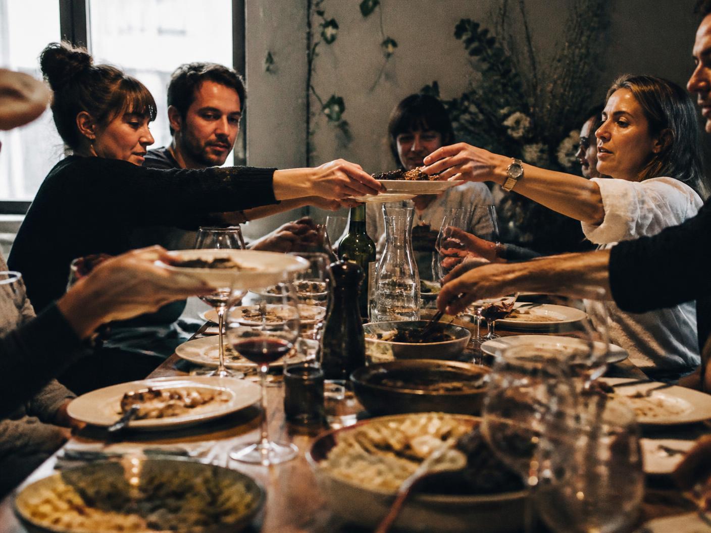Friends passing food around a busy shared table.